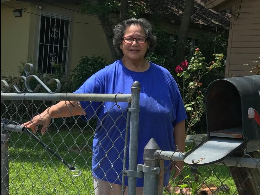 Sylvia Deleon standing in her yard just behind the gate.